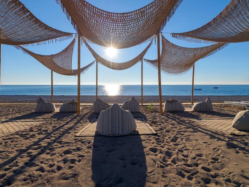 Tramonto sulla spiaggia con cuscini e reti d'ombra sulla sabbia.