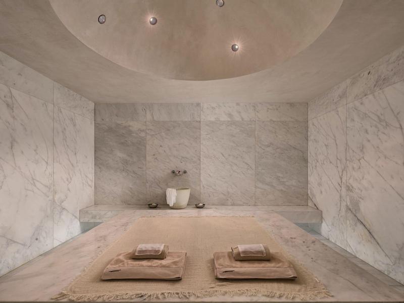 Sala spa moderna con pareti in marmo e due lettini con asciugamani.