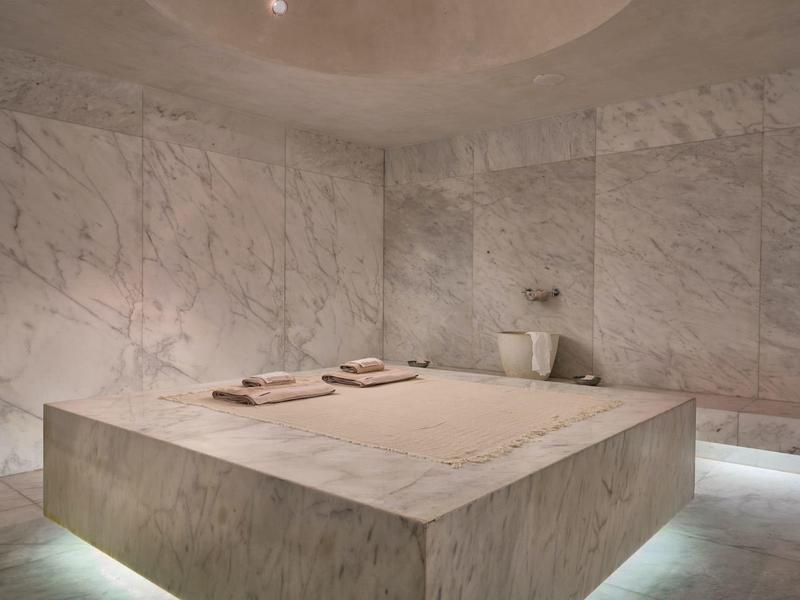 Stanza spa moderna con grande tavolo in marmo e pareti illuminate.