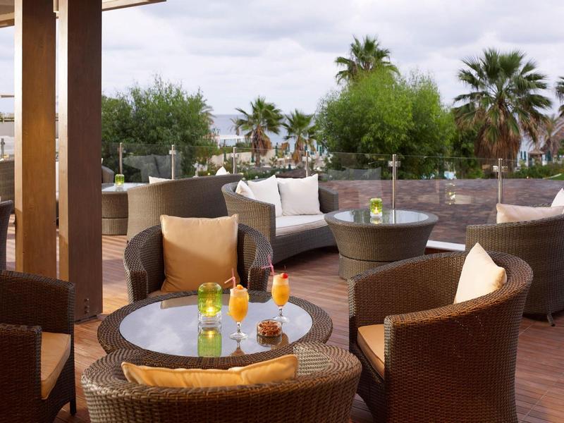 Terrazza con tavoli rotondi e sedie comode circondate da piante.