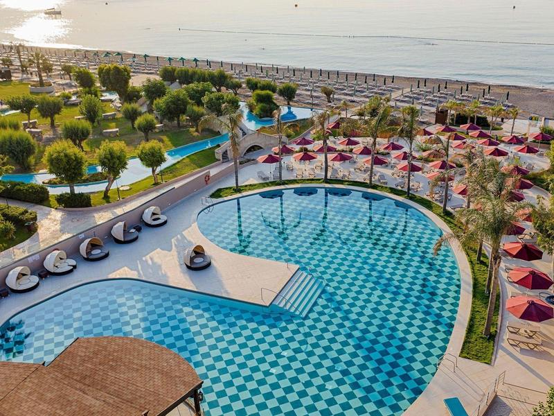 Area piscina lussuosa con lettini e vista mare in un hotel soleggiato.