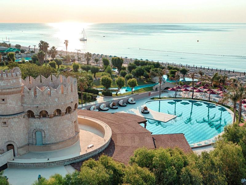 Torre rotonda accanto alla piscina con vista sul mare e palme in località turistica.