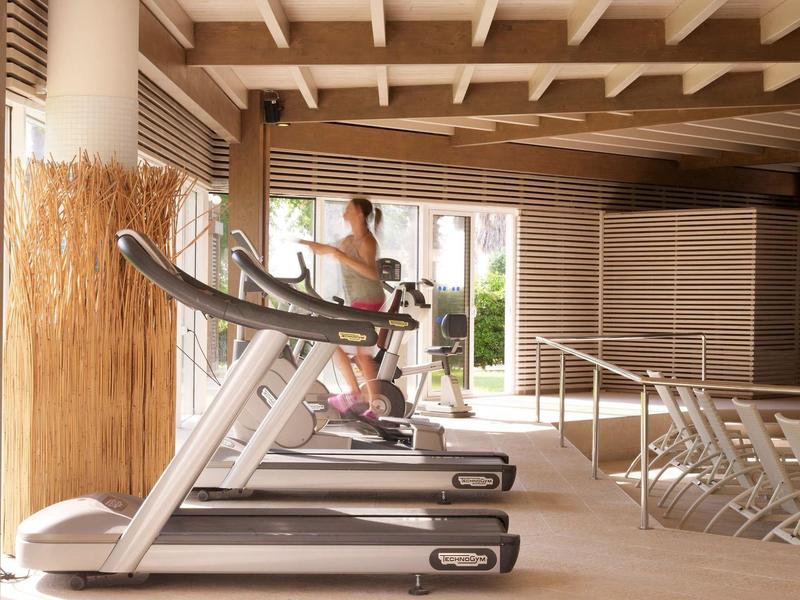 Donna si allena su un tapis roulant in una palestra moderna con luce naturale.