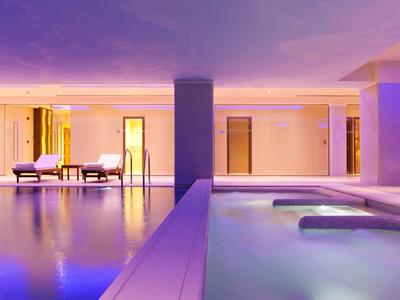 Piscina e jacuzzi interne moderne con illuminazione viola in un hotel.