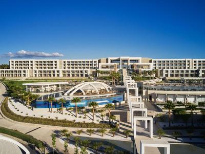 Moderner Hotelkomplex mit großen Pools, Brückenstrukturen und klar blauem Himmel.