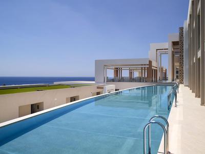 Piscina esterna moderna con vista sul mare e cielo azzurro in un hotel.