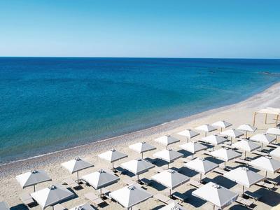 File di ombrelloni bianchi e lettini su una spiaggia sabbiosa vicino al mare azzurro e limpido.