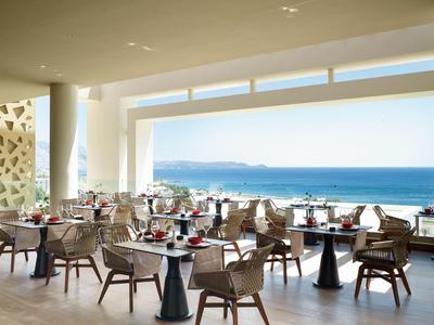 Zona pranzo con tavoli e sedie con vista panoramica sull'oceano sotto un cielo sereno.