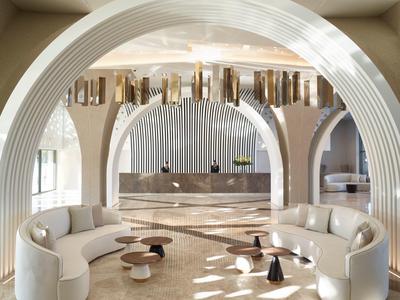 Elegante hall dell'hotel con divani bianchi curvi e tavoli moderni sotto soffitti ad arco.