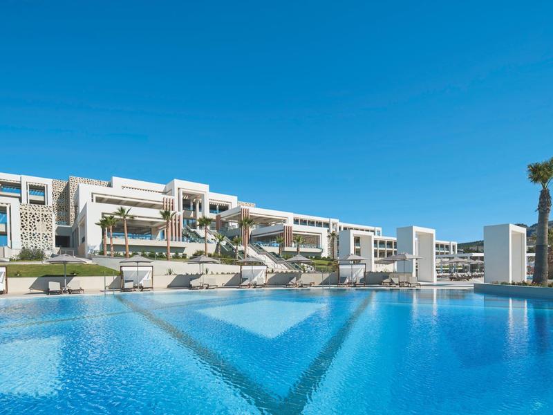 Hotel moderno con grande piscina all'aperto sotto un cielo azzurro
