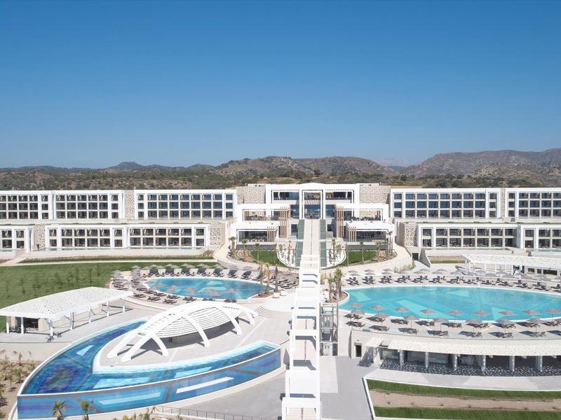 Resort moderno con grandi piscine e edifici bianchi su più piani sotto un cielo azzurro chiaro