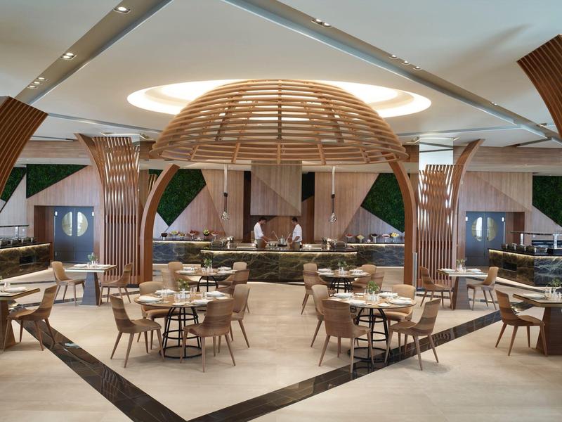 Ampia sala da pranzo dell'hotel con soffitto a cupola in legno e tavoli e sedie moderni.