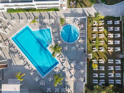 Widok z lotu ptaka na dwa baseny i leżaki w ogrodzie hotelowym