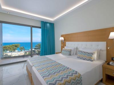 Habitación de hotel moderna con cama doble y vista al mar a través de grandes ventanales con balcón.