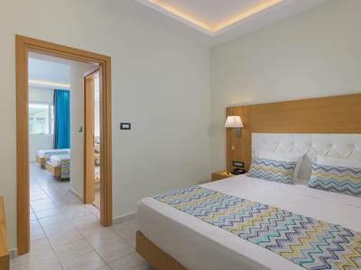 Dormitorio moderno con cama doble y vista a otra habitación con dos camas individuales.