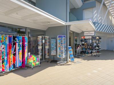 Mesas de venta con artículos de playa coloridos y souvenirs frente a un hotel