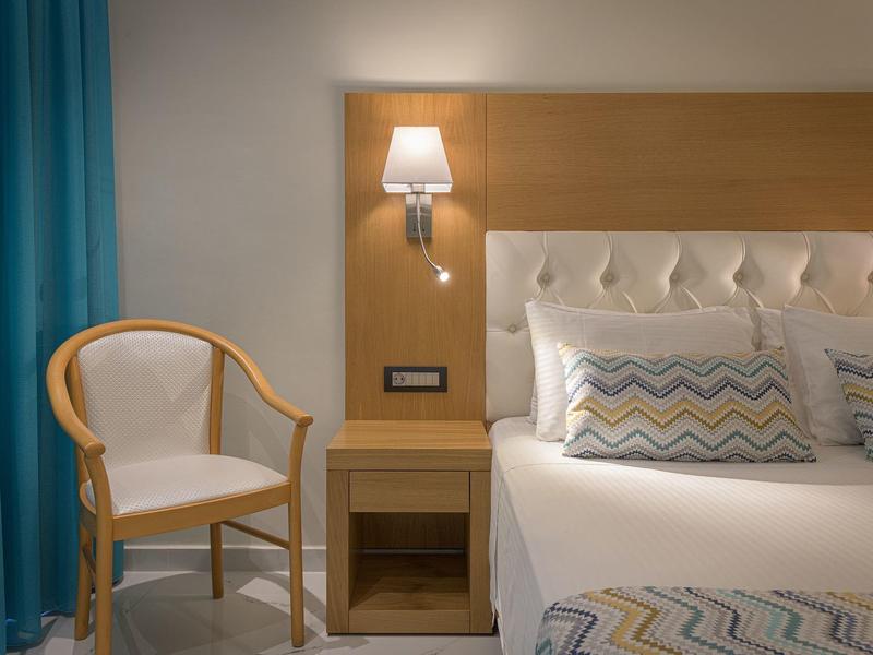 Habitación de hotel elegante con cama cómoda, mesita, silla y cortina azul.