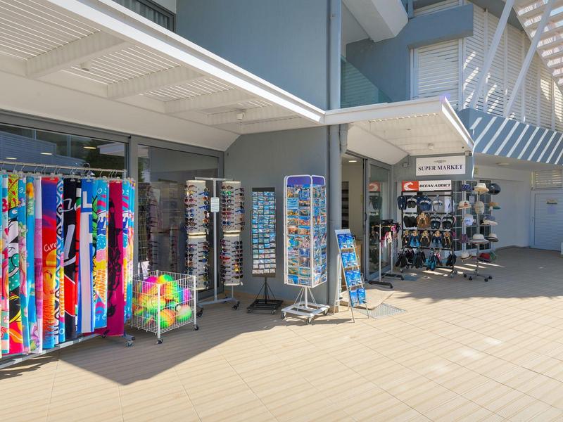 Mesas de venta con artículos de playa coloridos y souvenirs frente a un hotel