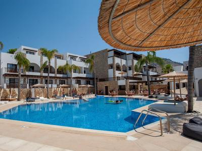 Moderner Hotelpool mit blauem Wasser, Sonnenschirmen aus Holz und weißen Gebäuden im Hintergrund.