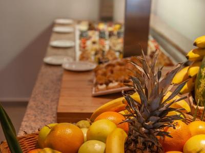 Korb mit verschiedenen Früchten wie Ananas, Bananen, Orangen und Äpfeln auf Tisch mit Teller.