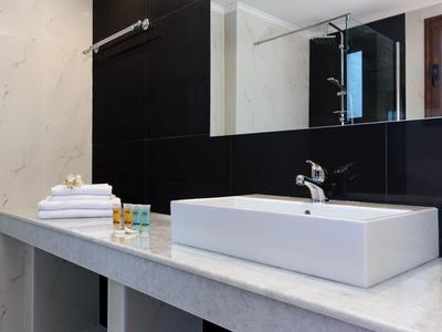 Moderner Badezimmerwaschtisch mit rechteckigem weißen Waschbecken, grauer Marmorplatte und schwarzer Rückwand.