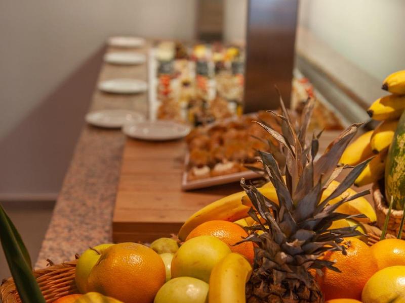 Cesta con frutas tropicales en un bufé de un restaurante de hotel, incluyendo piña y plátanos.