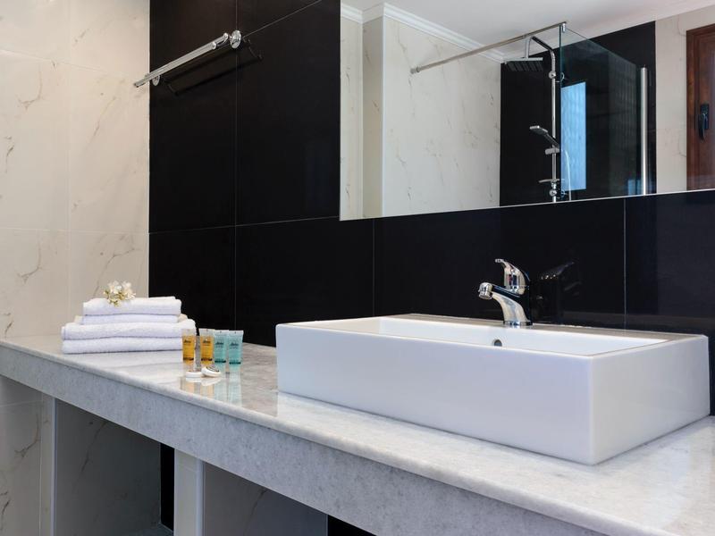 Área moderna de lavabo con lavabo rectangular blanco, encimera gris y paredes negras.