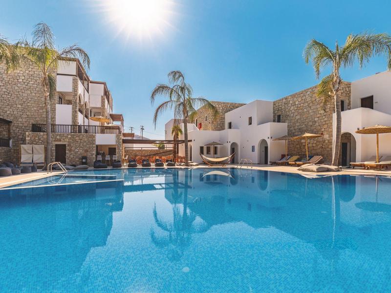 Piscina de hotel acogedora con palmeras y luz solar en un día despejado.