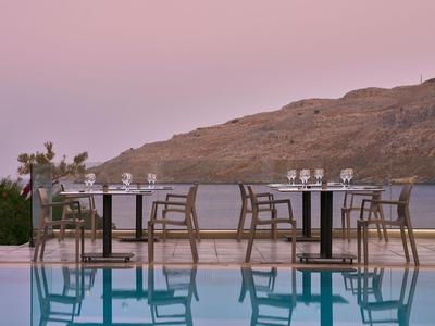 Chaises et tables vides à côté d'une piscine avec vue sur les montagnes au coucher du soleil.