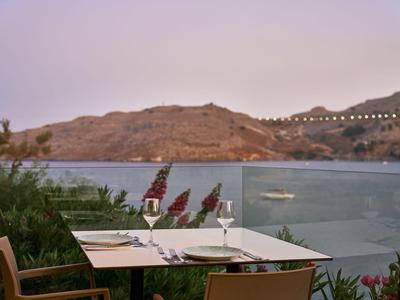 Terrasse avec table dressée face à la mer et collines en arrière-plan