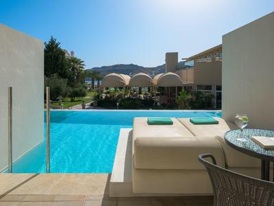 Uitzicht vanaf het zwembad met ligbedden, tafel en helderblauw water onder zonnige lucht.