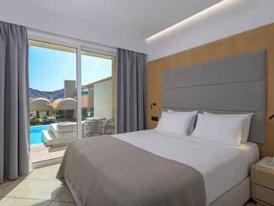 Moderne hotelkamer met tweepersoonsbed en schuifdeuren naar zwembad en uitzicht op de bergen.