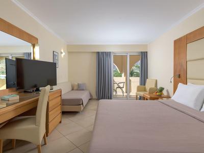 Moderne hotelkamer met tweepersoonsbed, bureau, tv, bank en balkon met zitje.