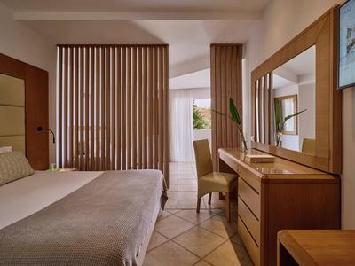 Gezellige hotelkamer met een bed, houten kaptafel, grote spiegel en patroon gordijnen.