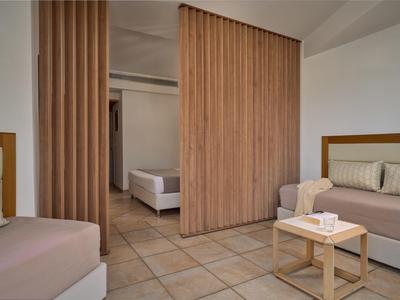 Moderne hotelkamer met bedden, bank, houten scheidingswand, betegelde vloer en klein tafeltje met doos tissues.