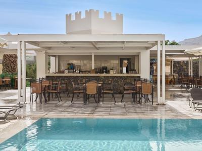 Piscine extérieure moderne avec bar et sièges sous un soleil éclatant.
