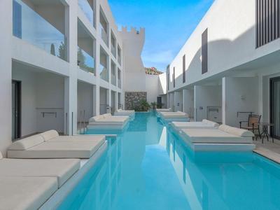 Modern hotelzwembad met ligbedden en balkons onder heldere lucht