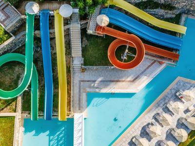 Buitenwaterpark met meerdere kleurrijke glijbanen en een zwembad omringd door ligstoelen.