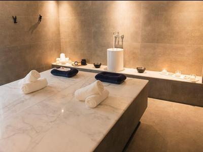 Moderne spa kamer met marmeren massagetafel, zachte handdoeken en warme sfeerverlichting.