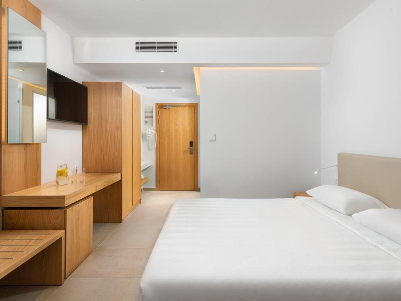 Minimalistische hotelkamer met wit bed, houten meubels en neutrale tinten.