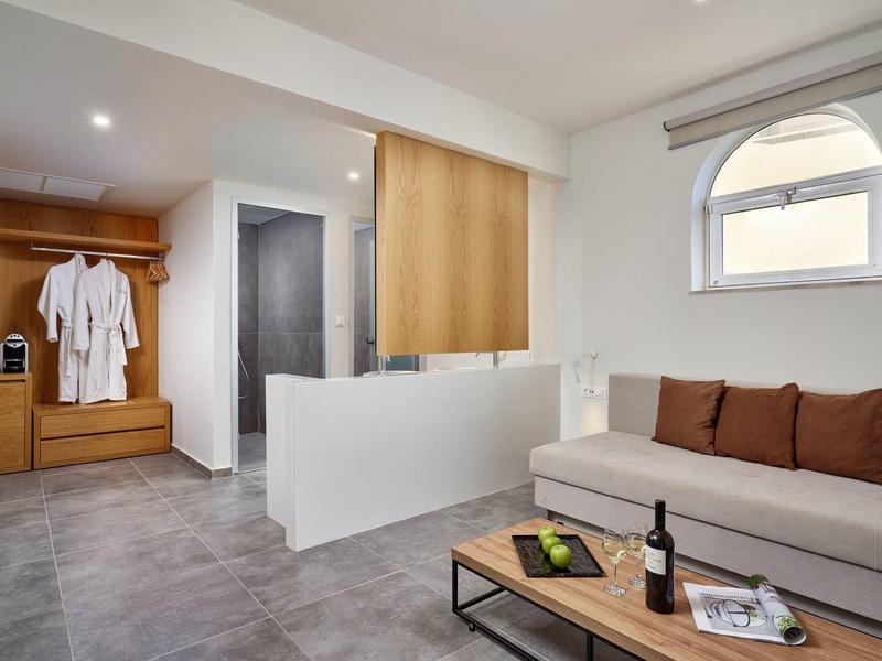 Moderne hotelkamer met bank, salontafel, badjassen en houten garderobe.