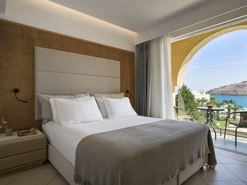 Gezellige hotelkamer met een tweepersoonsbed en een balkon met uitzicht op zee.