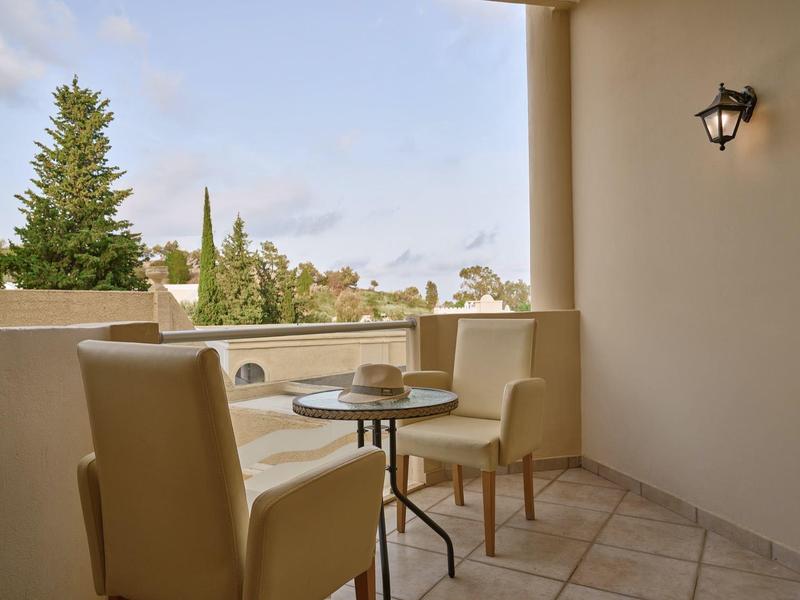 Gezellig balkon met tafel en stoelen met uitzicht op groen onder een blauwe lucht.