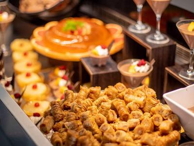 Buffet mit Gebäck, Obsttorte, kleinen Desserts und Fruchtschalen in einem schwarzen Behälter.