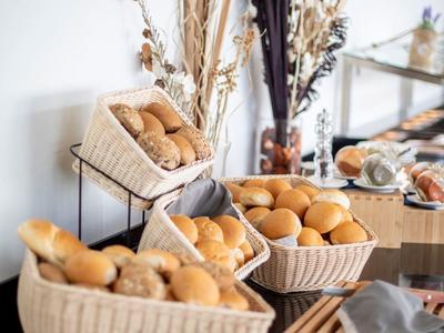 Mehrere Körbe mit Brötchen stehen auf einem Tisch, dahinter getrocknete Blumen als Dekoration.