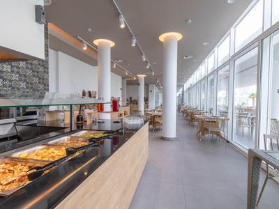 Moderne Cafeteria mit Buffet, großen Fenstern und hellem, offenem Raum.