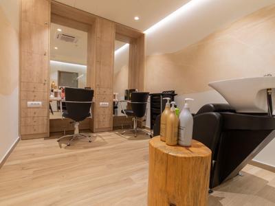 Moderner Friseursalon mit hellen Holzmöbeln, zwei Spiegeln, Friseurstühlen und Waschbecken.
