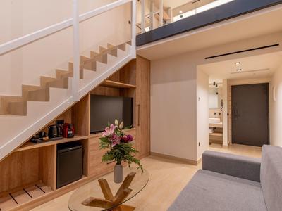 Moderner Wohnraum mit Holztreppe, Glas-Couchtisch, grauem Sofa und eingebautem Schrank.