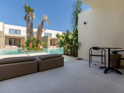 Moderner Außenbereich mit Pool, Palmen, Lounge-Möbeln und klarem blauem Himmel.