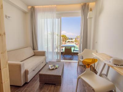 Heller Raum mit Sofa, Behandlungsstuhl, Massagebank und Balkon mit Meerblick.